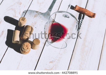 Wine glass, cork and corkscrew over wooden table