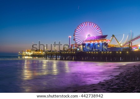 Santa Monica Pier illuminated with new LED lights at night with a reflection that can be seen on the waves. Royalty-Free Stock Photo #442738942