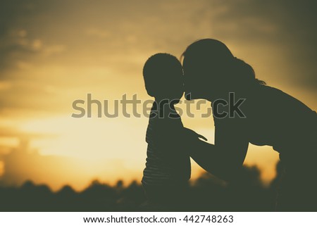 Silhouette of a family comprising mother and children at sunset Royalty-Free Stock Photo #442748263