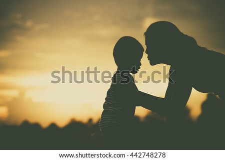 Silhouette of a family comprising mother and children at sunset Royalty-Free Stock Photo #442748278