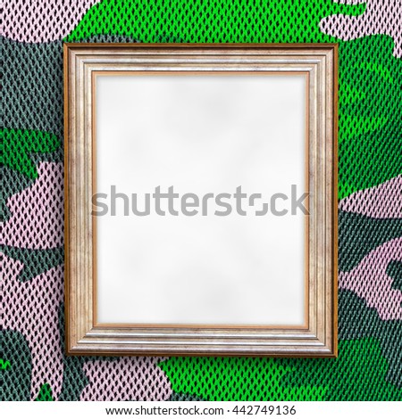 Blank of wooden photo frame on military pattern fabric background.