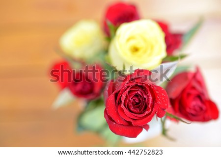 red &yellow roses in vase with water droplets 