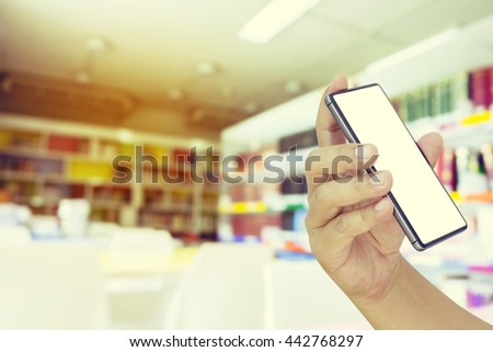 Man hand holding mobile smart phone ,tablet, Blurred abstract background view of book shelves in public school library - Vintage effect filter style pictures.