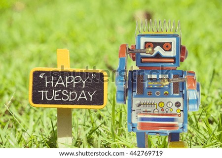 Happy Tuesday word. Toy robot with sign on green grass, day and time concepts - Vintage effect filter style pictures