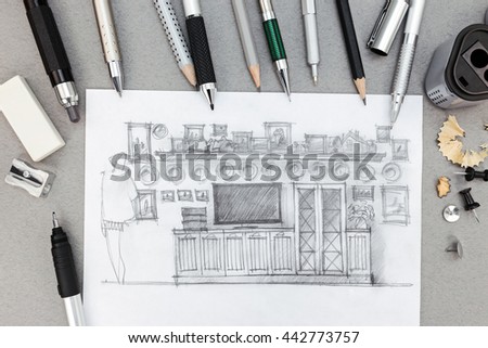 designer workplace with freehand sketch of wall unit and drawing tools