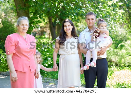big family and pregnant woman in city park, summer season, green grass and trees