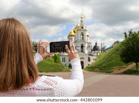 Girl taking pictures on mobile smart phone in front view Temple in the town of Dmitrov