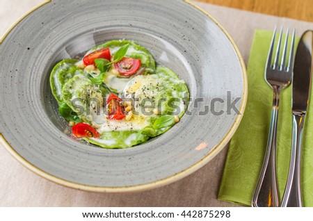Ravioli with spinach , cheese and cherry tomatoes . Italian food in the restaurant on a table close-up .

