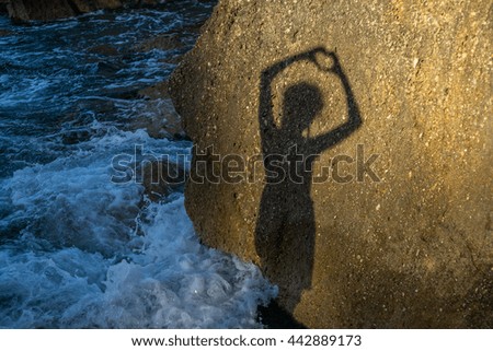 Girl makes heart shape shadow on a rock at the beach