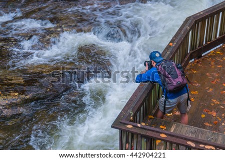 A traveller or photographer is taking pictures of a waterfall during fall foliage season, Virginia, USA