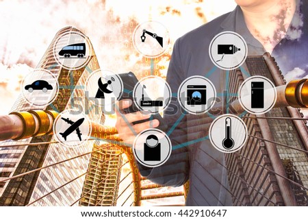 The Internet of Things concept. Internet of Things wireless network against double exposure of man using smart phone and city infrastructure with binary code background.