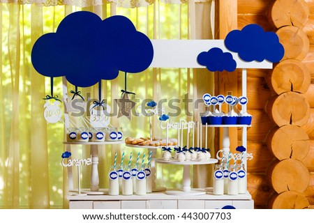 Candy bar on baby's christening party with a lot of different candies and beverages. Decorated in blue colors, clouds theme, indoor Royalty-Free Stock Photo #443007703