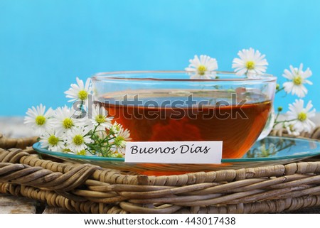 Buenos dias (which means Good morning in Spanish) with cup of chamomile tea on blue background
