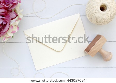 Mockup of envelope with a rubber stamp next to it. Modern trend template for advertising. Flowers and wooden background.
