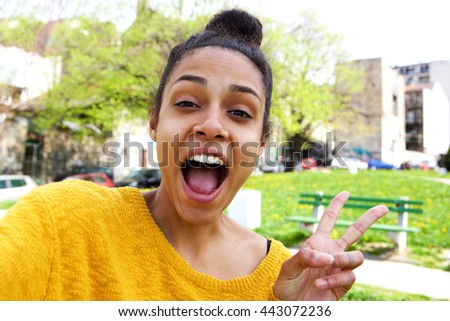 Close up portrait of excited young african american woman taking selfie with peace sign 
