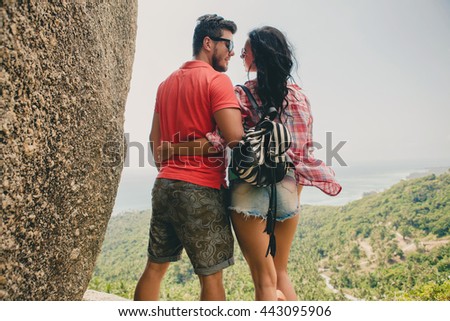young couple in love standing on mountain, landscape background, view from back, romantic vacation, traveling around the world, hugging, looking at each other, tourist outfit