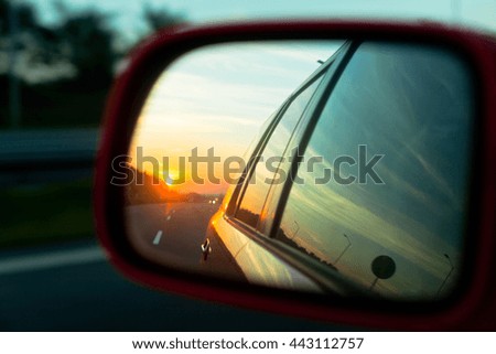 Sunset reflection in the rear view mirror of a car on a highway. Blur shot Royalty-Free Stock Photo #443112757