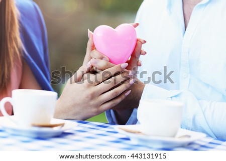 Picture of romantic couple holding hands in cafe