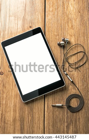headphones and tablet on a wooden surface