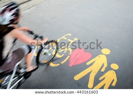 Cyclist in motion passing by the pedestrian/bicylce sign with heart graffiti on the road in Budapest  