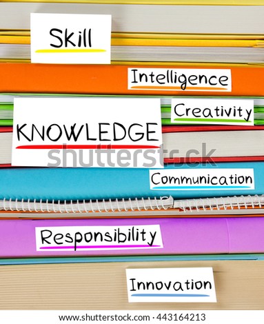 Photo of colorful book stack with bookmarks and labels with KNOWLEDGE conceptual words