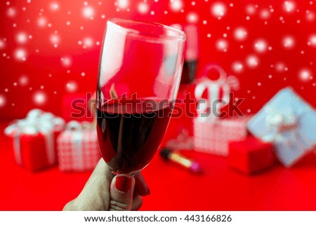 Red wine and Christmas ornaments on snow on red background