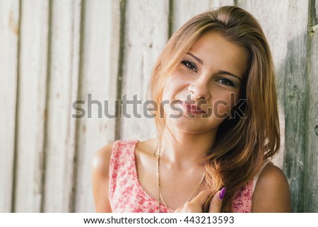 Fashion young blonde woman in pink T shirt smiling over pale wooden background
