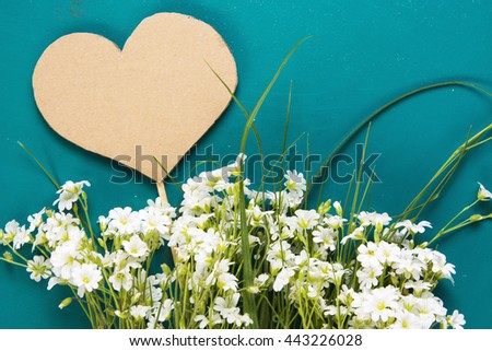 Fresh  flowers on turquoise painted wooden planks. heart note Romantic date, invitation, sweet wish concept. Selective focus. Place for text. Toned image.