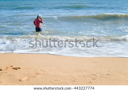 Amazing young male talking on mobile phone, storm wave beach background