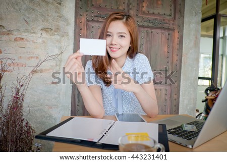 Beautiful business woman using a laptop computer,showing blank name card