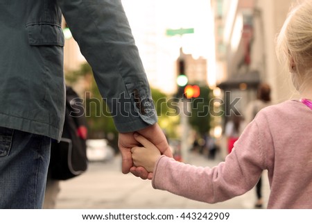 father holding  the daughter/ child  hand  behind  the traffic lights
