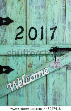 Year 2017 in black iron numbers, Welcome and tin heart hanging on antique rustic mint green wood door