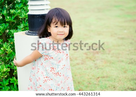 Portrait of a cute little asian girl in sunny summer day at green nature background