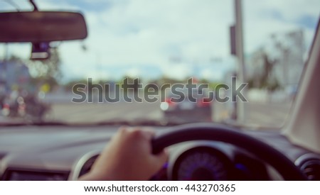 vintage tone blur image of people driving car on day time for background usage.(take photo from inside)