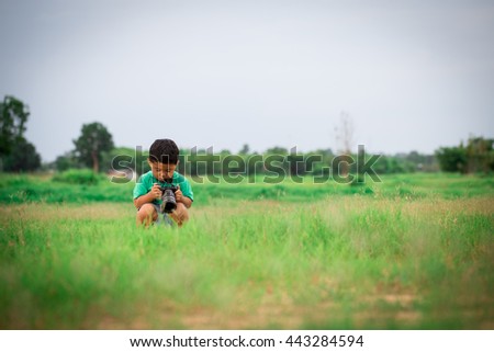 Young photographer takes pictures on the green field.