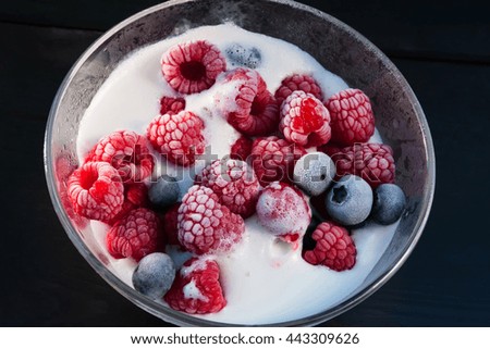 Frozen raspberry and blueberry with ice cream in a glass bowl