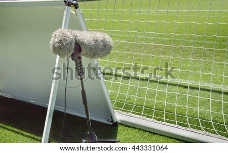 furry sport microphone on a soccer field behind the goal net in sunny day