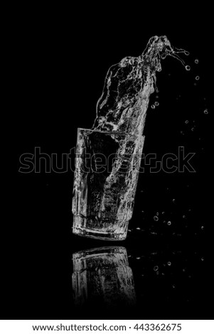 Drinking water splash out of glass on a black background.