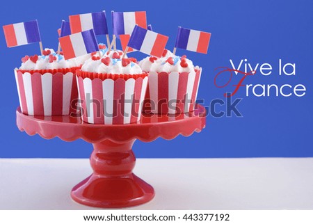 Happy Bastille Day red, white and blue cupcakes on red cakestand on blue and white background. 