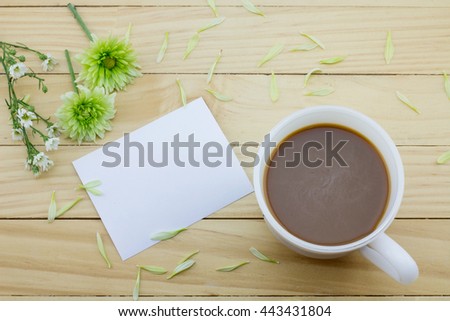 Coffee mug with White daisy flowers and notes on yellow rustic table.flower petals