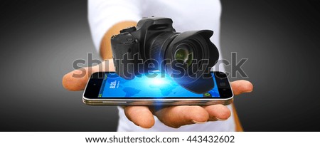 Young man holding modern digital camera over his mobile phone