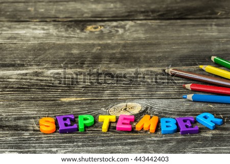 school supplies on wooden background, colorful pencils with the word September