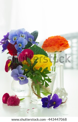 Colorful vibrant cut flowers in vases on white table