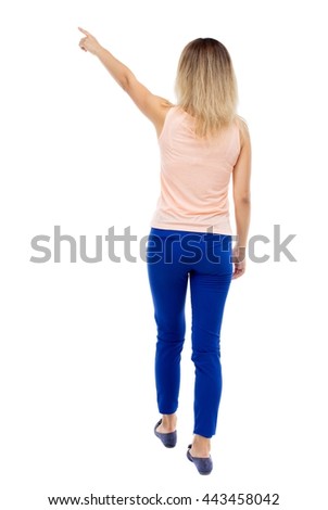 Back view of  pointing woman. beautiful girl. Rear view people collection.  backside view of person.  Isolated over white background. Blonde in blue pants and a pink blouse is pointing.