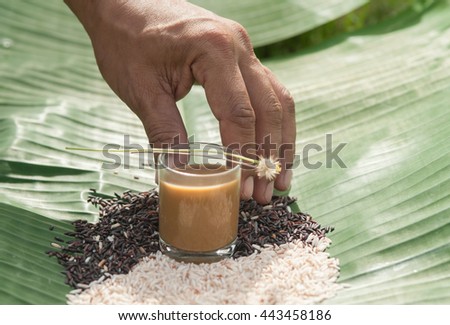 Handlebar coffee cup of hot coffee tree in one mixed brown rice on banana leaf.
