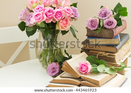Pile of old books with bouqet of pink rose flowers