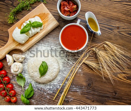 Pizza dough with ingredients and tomato sauce served on rustic wooden table. Aerial shot, copyspace for text