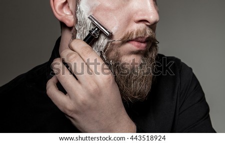 
close-up of a man with a long beard and a mustache , beard shaves with a straight razor Royalty-Free Stock Photo #443518924