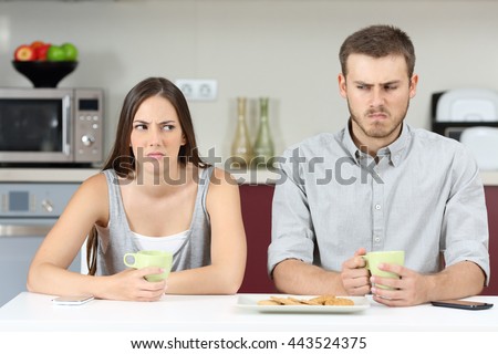 Front view of an angry couple looking each other sideways after argument in the kitchen during breakfast at home Royalty-Free Stock Photo #443524375