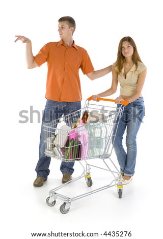 Young couple with trolley. Homosexual boy showing something bored girl. Isilated on white in studio. Whole body, front view